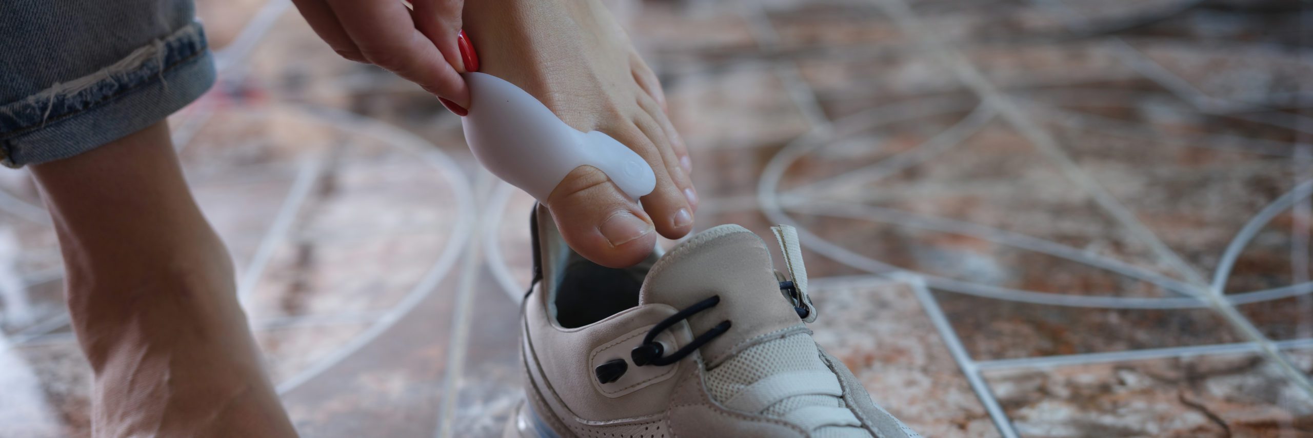 A woman is putting on a shoe that has a bunion pad inserted in it to help alleviate pain and pressure on the bunion.
