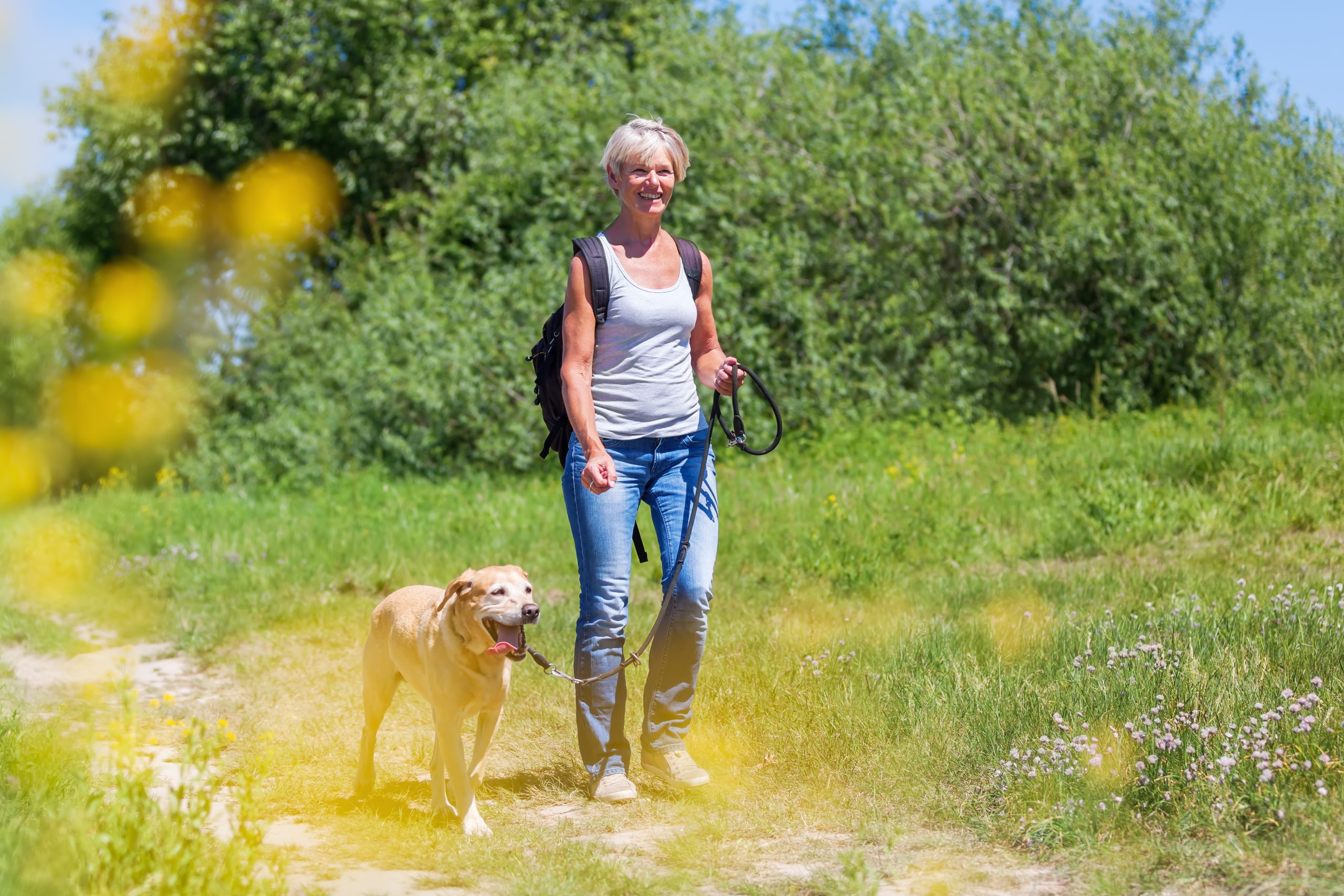A woman with diabetes, hammer toes, and bunions happily walking her dog, showing that with the right fit of footwear, one can still enjoy daily activities and maintain an active lifestyle.