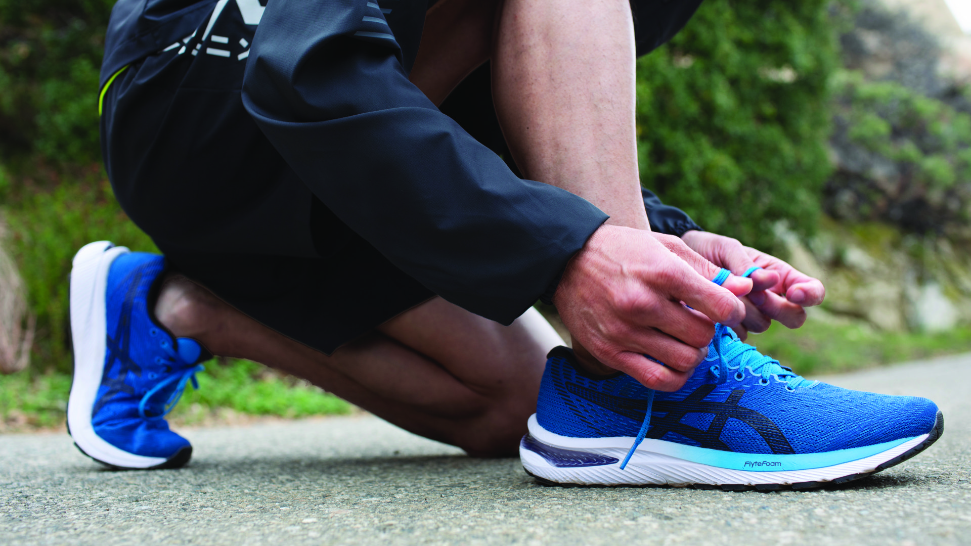 A picture of a runner wearing a pair of blue Asics Gel Kayano shoes, these shoes are known for their cushioning and structure. The shoes have a gel cushioning system that provides a comfortable and responsive ride, this can help to reduce the impact of each step and alleviate pressure on the back. They are perfect for runners and people who engage in high-impact activities, and are looking for a shoe that can help with their back pain.