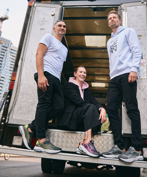 A group of people sitting on the back of a truck, modelling Waldlaufer footwear.